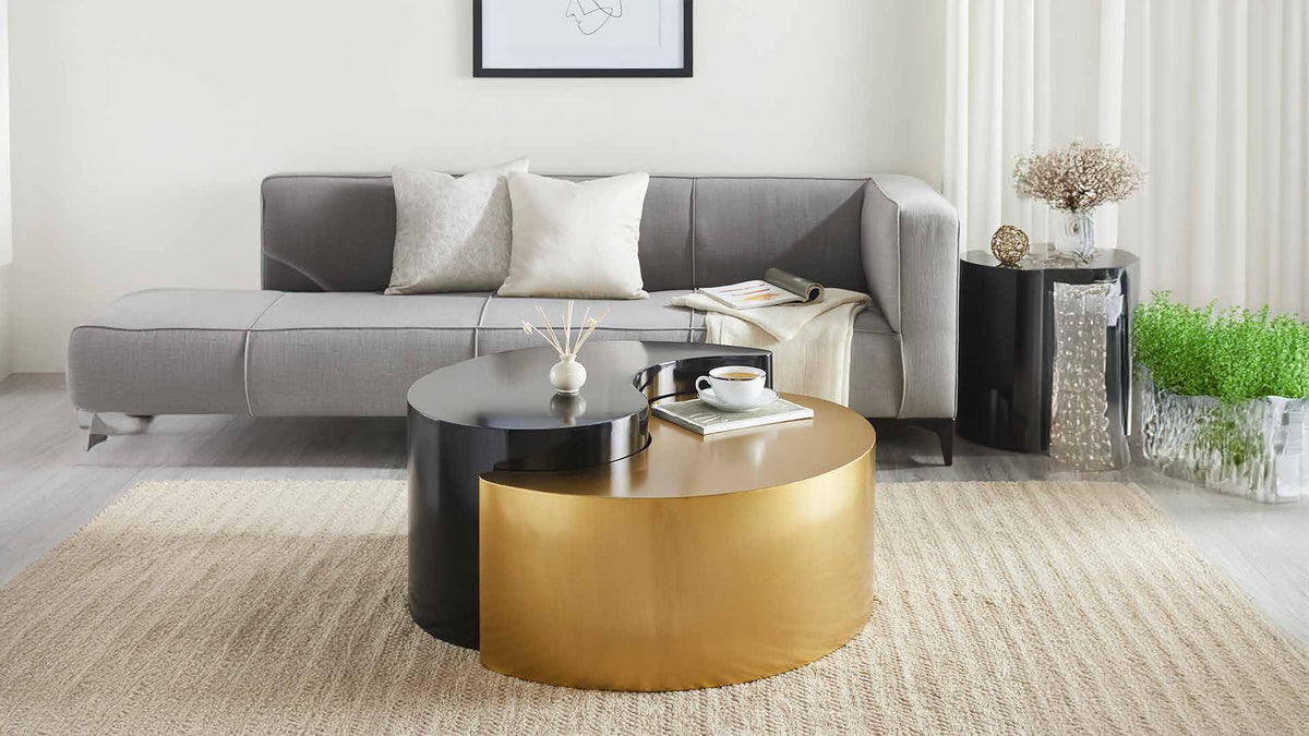 Ying Yang Black & Gold coffee table in the foreground of a room scene with seating and a separate end table.