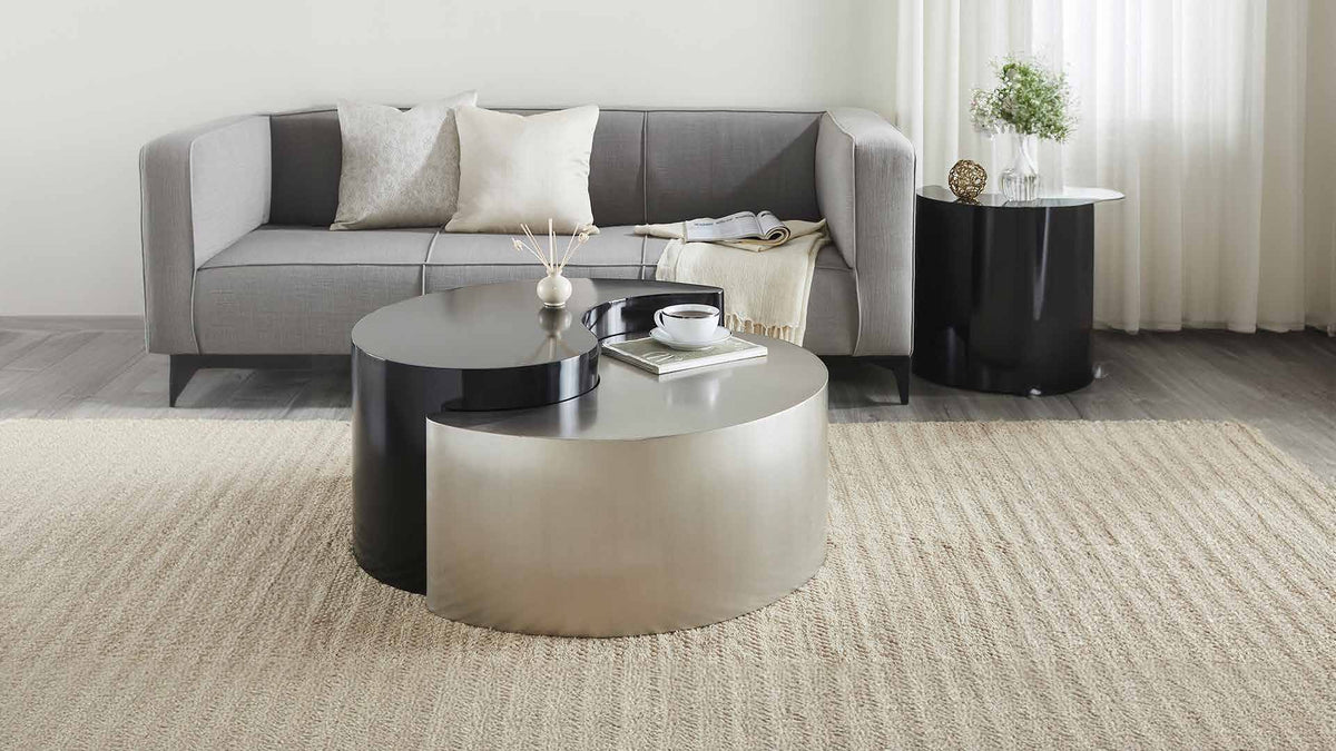 Ying Yang Black & Silver coffee table in the foreground of a room scene with seating and a separate end table.