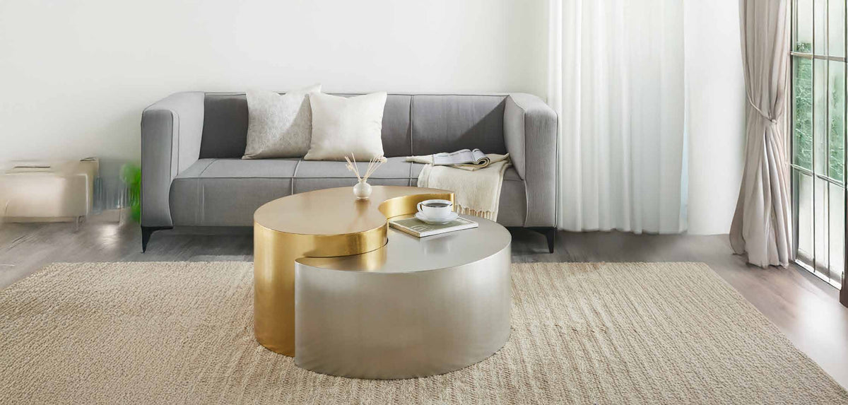 Ying Yang Gold & Silver coffee table in the foreground of a room scene with seating and a separate end table.